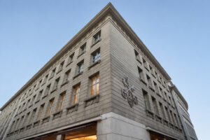 Vue en contre-plongée du bâtiment du Credit Suisse avec son emblème de clés croisées sous un ciel bleu.